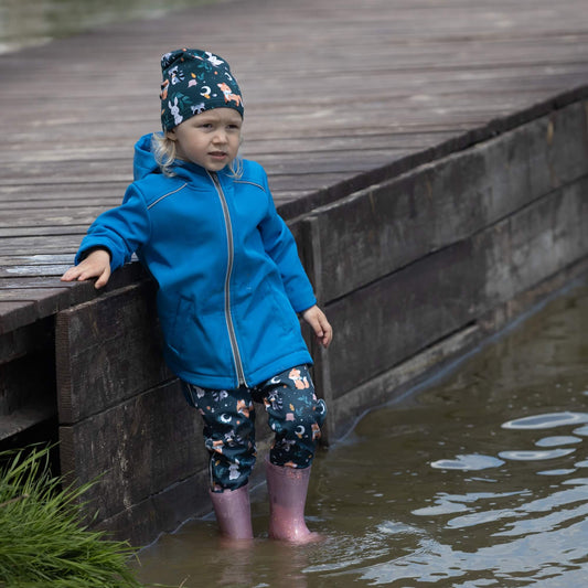 Dziecko w spodniach softshell z wzorem liści bawiące się w wodzie